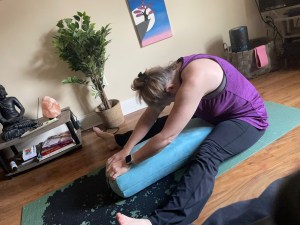 Demonstrating seated wide-legged pose with bolster